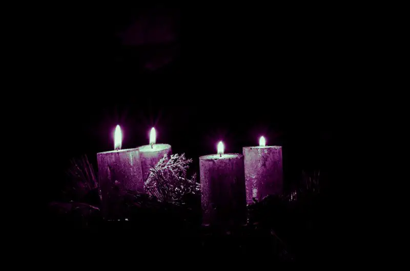 can annyone advent concept with four silver burning candle on black background violet tone